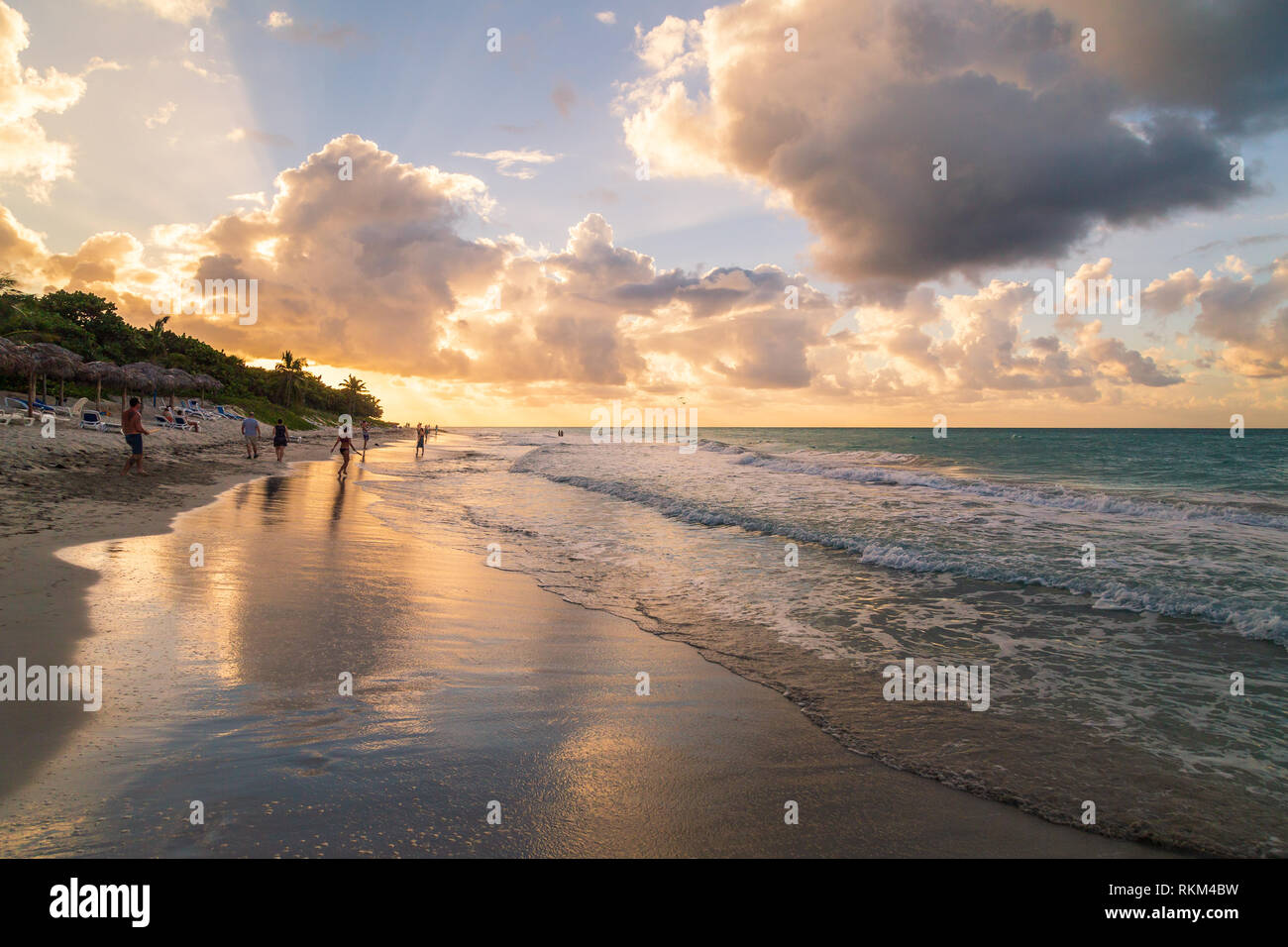 Cielo e nubi riflessi nella sabbia della spiaggia di Varadero in una giornata di sole con la gente a piedi lungo, Hotel Sol Palmeras, Cuba Foto Stock