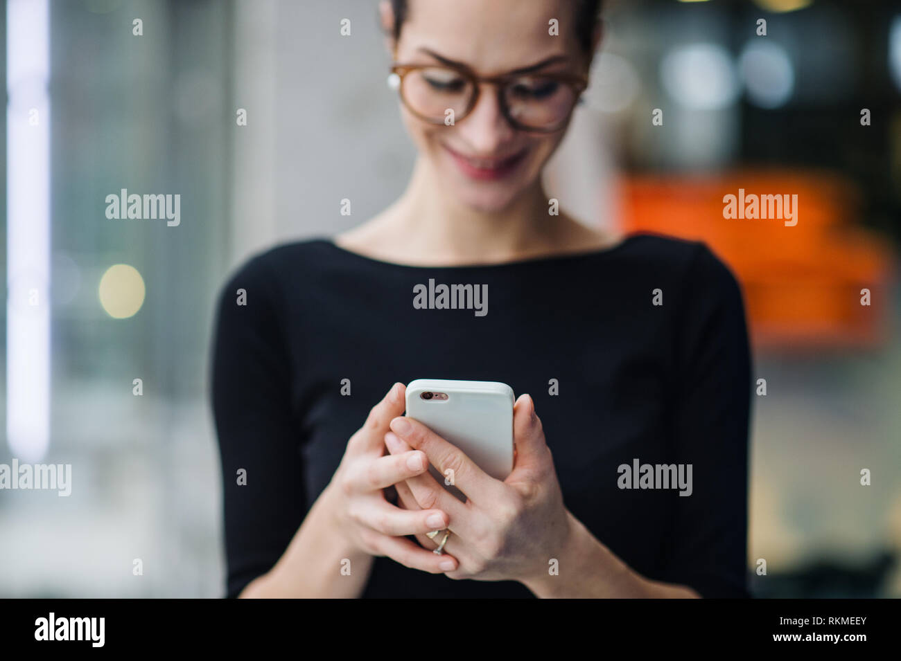 Una giovane donna di affari con lo smartphone in piedi in ufficio. Foto Stock