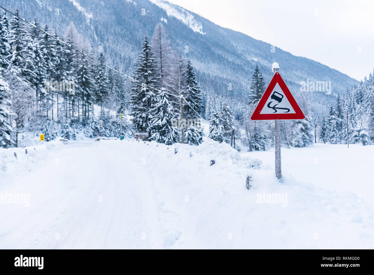 Black Ice pericolo - glatteisgefahr segno di traffico, avviso servizi invernali, Schladming Dachstein. Coperta di neve su strada e alberi. Austria, Europa Foto Stock