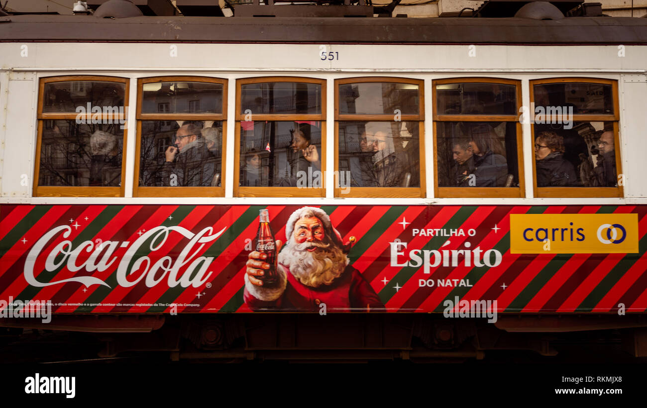 Lisbona, Portogallo - 01/03/19: Tradizionale giallo vecchio tram elettrico nel centro di Lisbona. Vista laterale con passeggeri e windows, vino Coke, Coca-cola adve Foto Stock