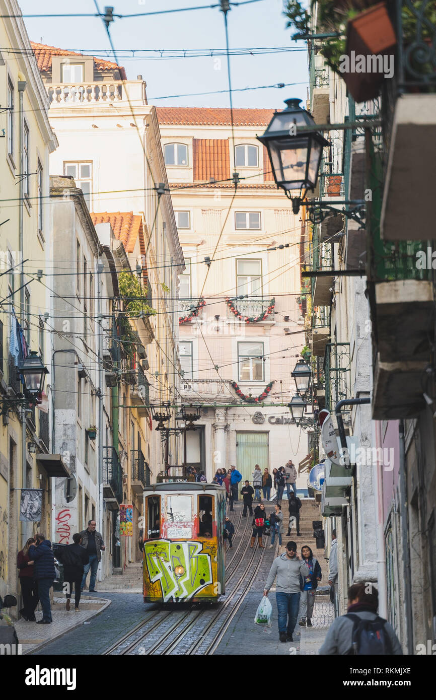 Lisbona, Portogallo - 01/03/19: cavo elettrico tram ascensore in salita e in discesa su una collina. Un sacco di persone in strada stretta con gli edifici di cavi e balco Foto Stock