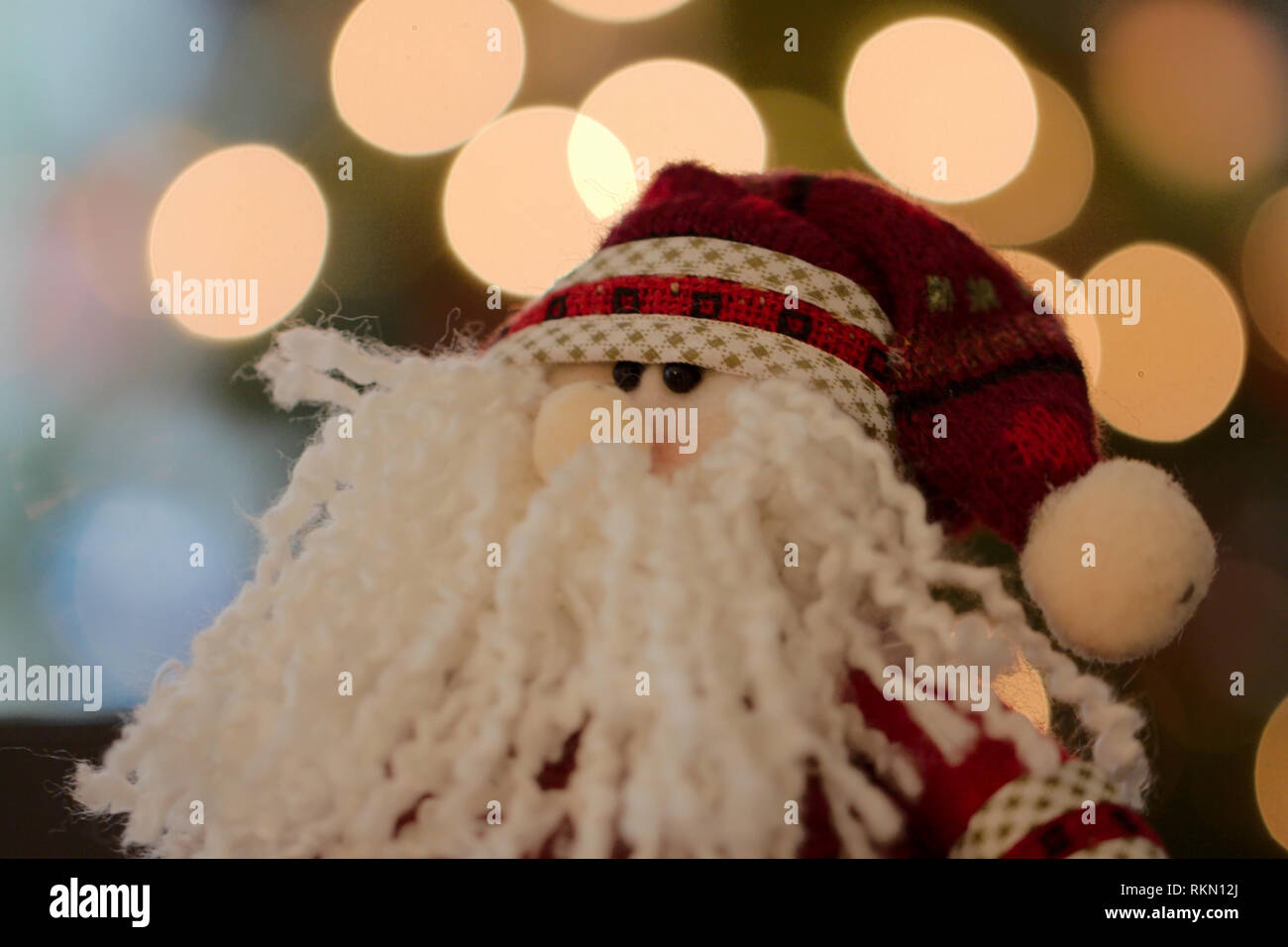 Santa bambola con folta barba di filato e beady gli occhi di fronte di luci ad albero bokeh di fondo Foto Stock