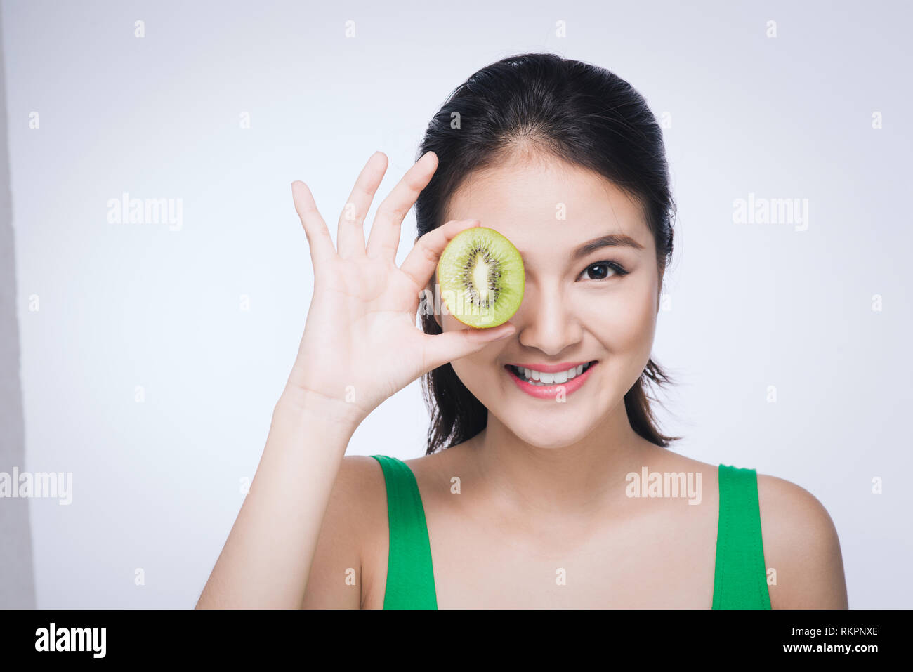 I kiwi. Felice giovane donna asiatica holding kiwi isolati su sfondo bianco Foto Stock