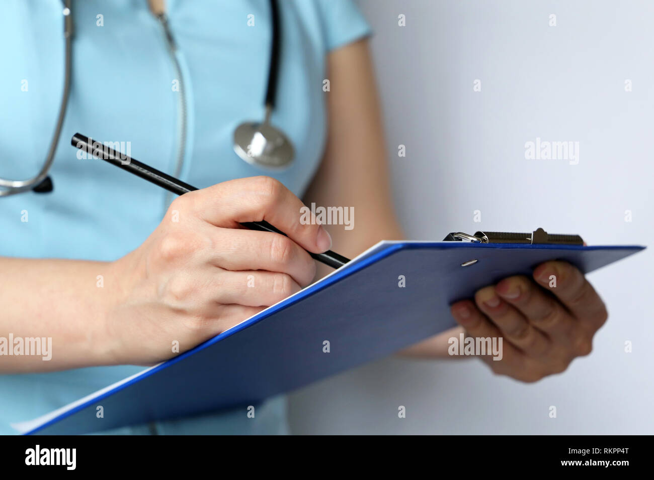 Medical Exam, donna medico o infermiere con uno stetoscopio scrive una prescrizione della carta. Concetto di medicina, di diagnosi, di esame presso la clinica Foto Stock