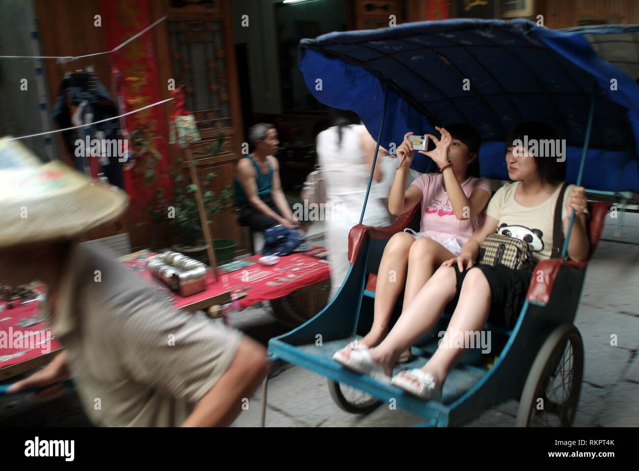 Un rickshaw driver tirando i turisti attraverso i vicoli di Fenghaung. Significato 'Phoenix' in cinese, Fenghuang è stato chiamato dopo il mitico uccello di Foto Stock