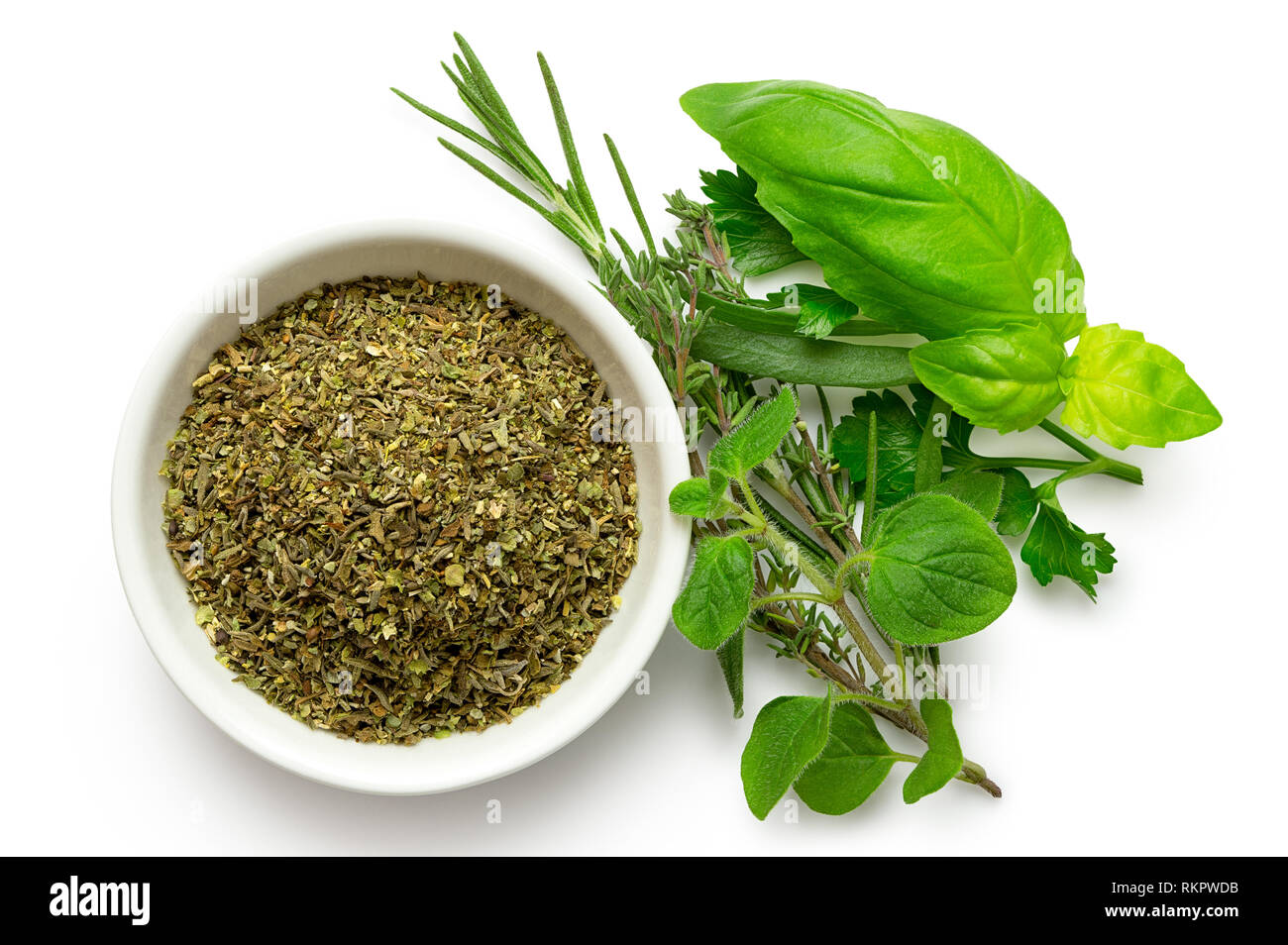 Essiccato trito di erbe di Provenza in un bianco di ceramica ciotola accanto al bouquet fresco garni isolato su bianco dal di sopra. Foto Stock