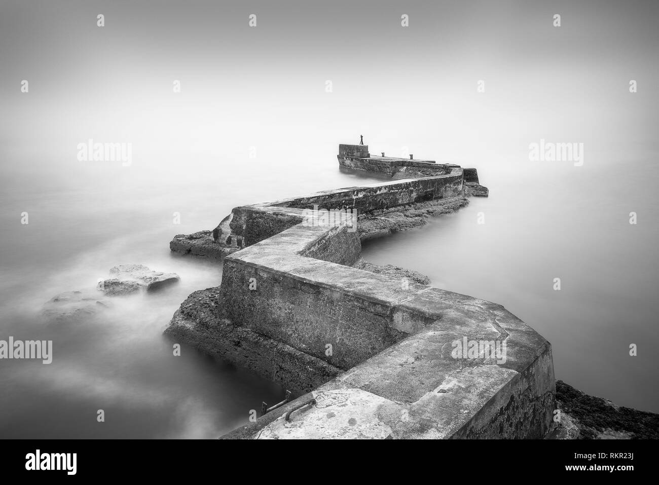 Una lunga esposizione di un insolito a zig zag molo di pietra che sfocia nel mare del Nord a st monans, Scozia Foto Stock