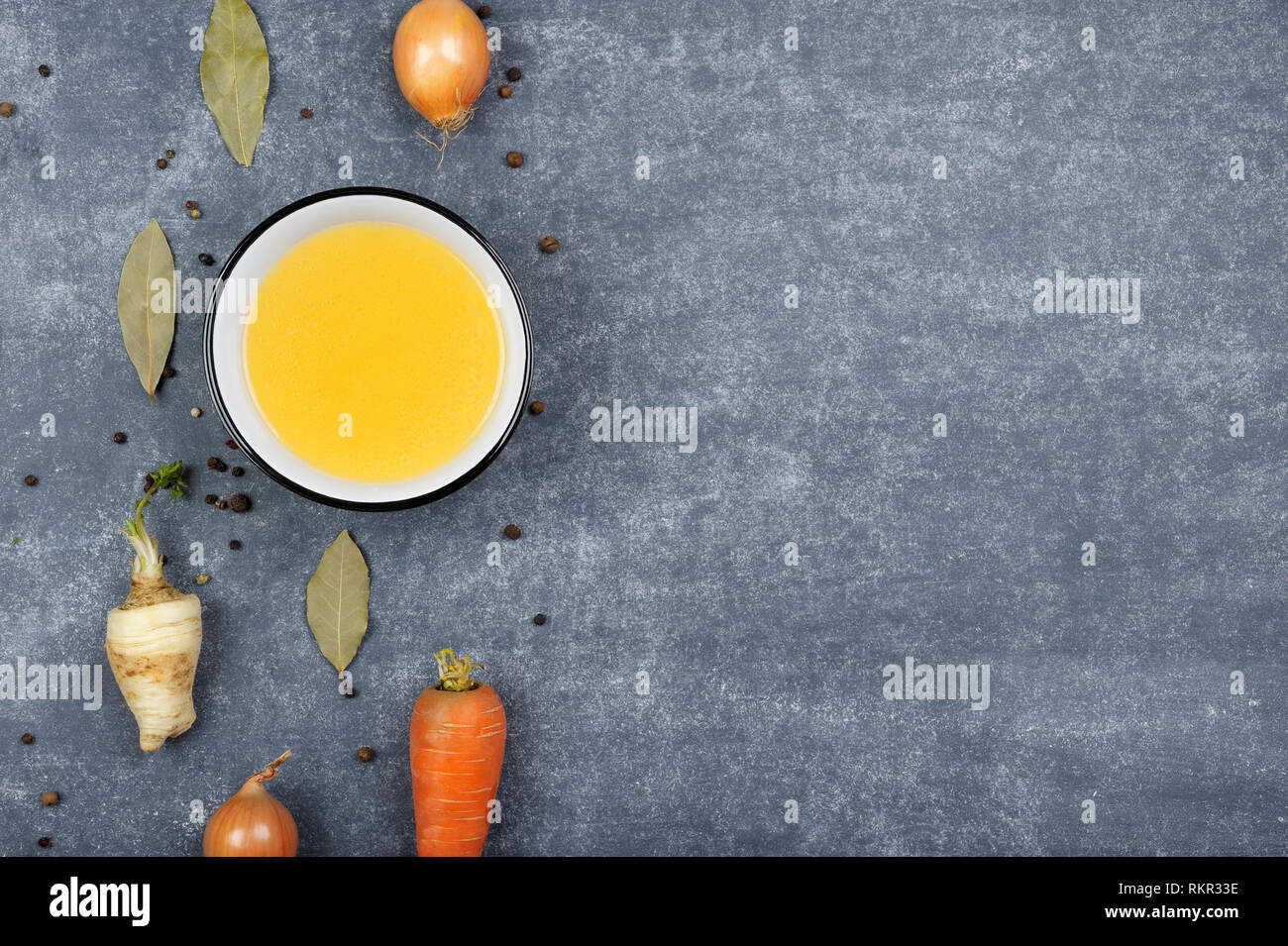 Brodo con ingredienti.chiara brodo è realizzato facendo sobbollire la carne o ossa o verdure. Preparato con pepe, carota, cipolla, prezzemolo radice, sedano.il cibo. Foto Stock