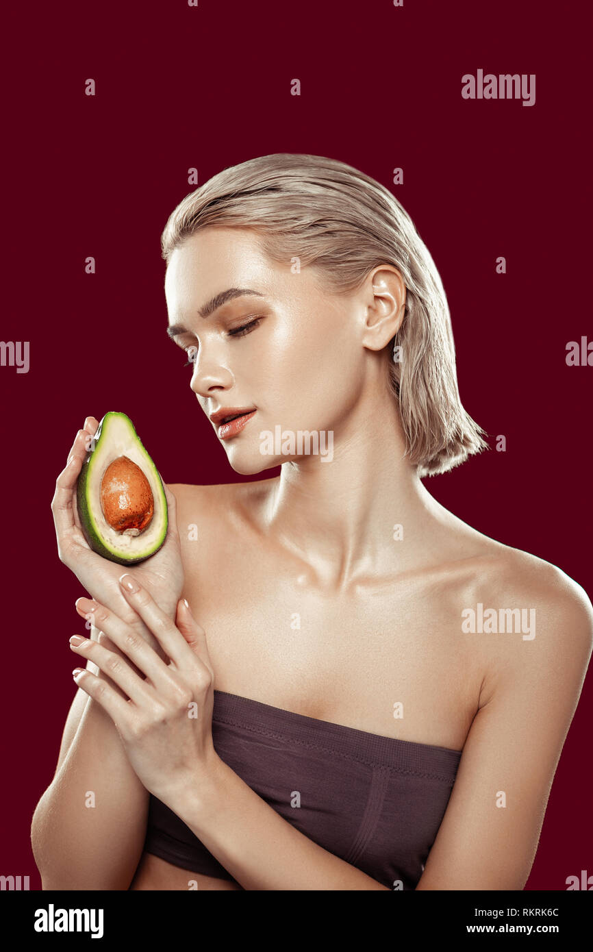 Bionda che indossa il modello dark top holding avocado Foto Stock