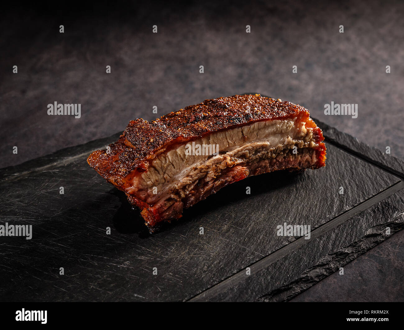 Grigliata di carne di maiale barbecue nervature su un nero ardesia tagliere Foto Stock