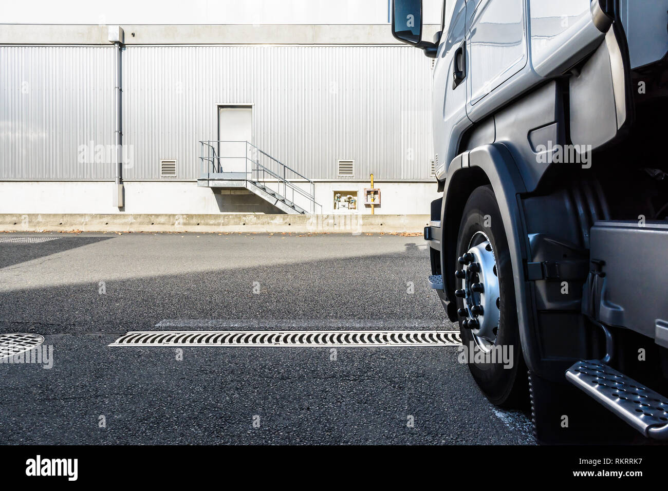 Un semirimorchio carrello parcheggiato di fronte ad un edificio industriale coperta con un grigio ferro corrugato schierandosi con uno sportello nella parte superiore di una piccola scalinata. Foto Stock