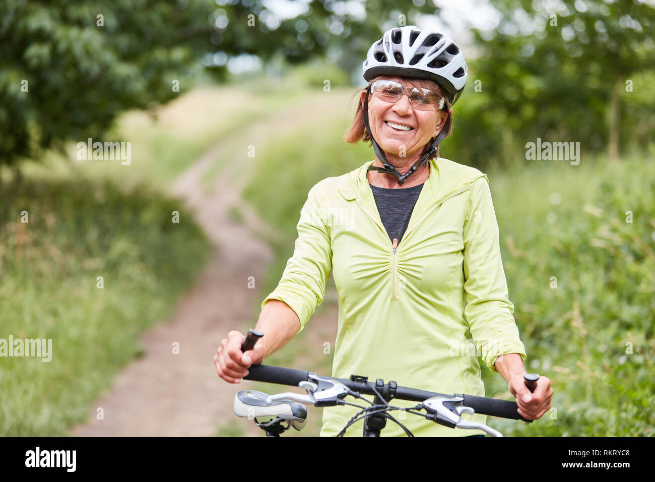 Vitale donna senior con casco per bicicletta e mountain bike fa un giro in bici Foto Stock