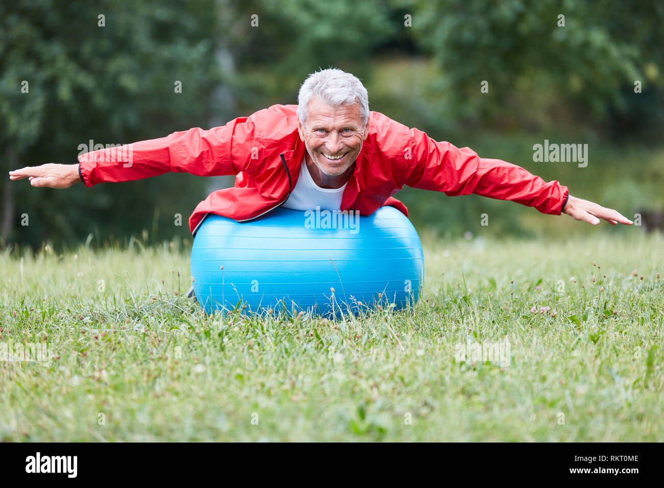 Senior saldi uomo durante un esercizio indietro su una palla ginnica nel parco Foto Stock