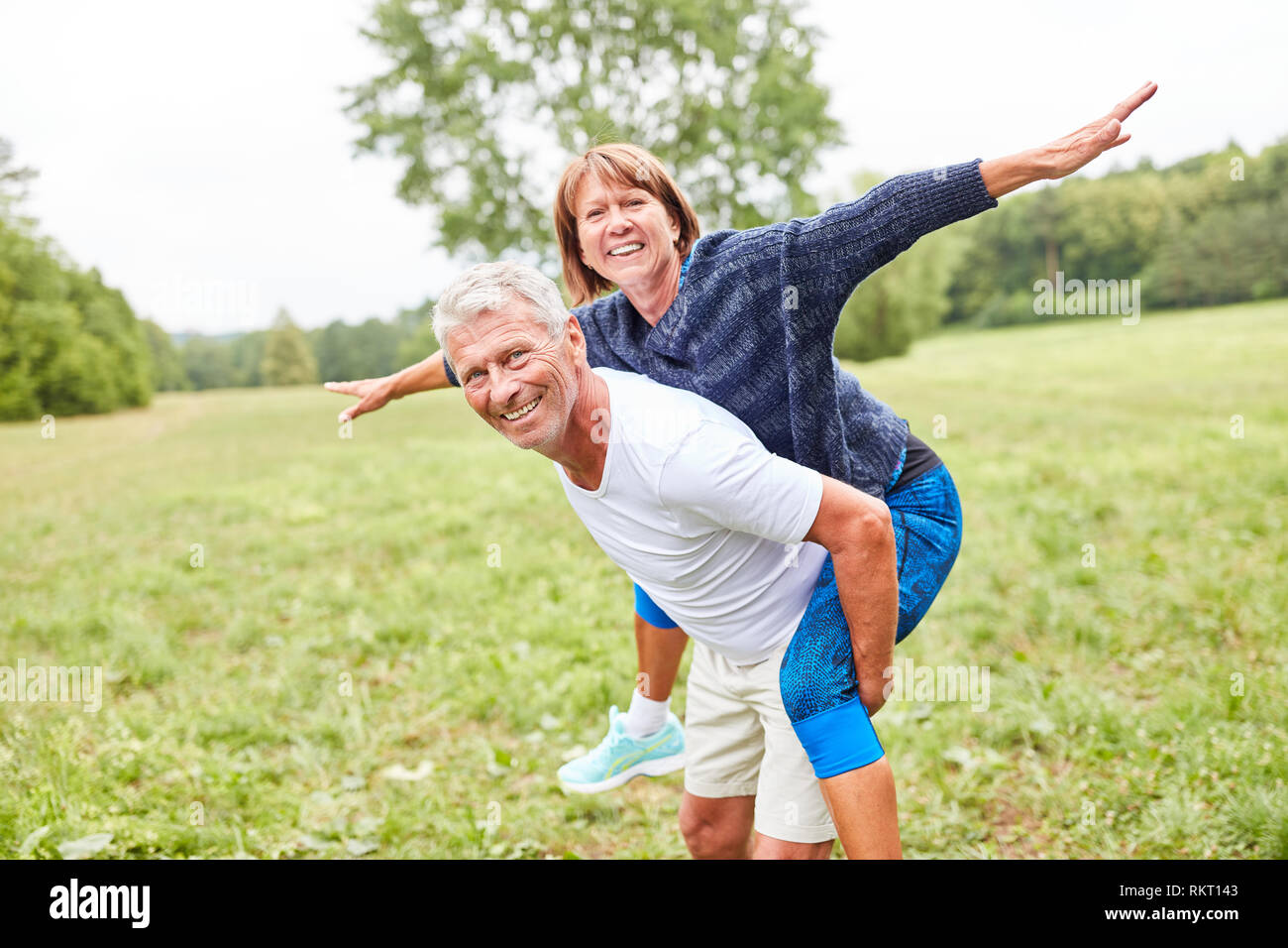 Senior donna corse piggyback sulla sua compagna di nuovo nel parco in estate Foto Stock