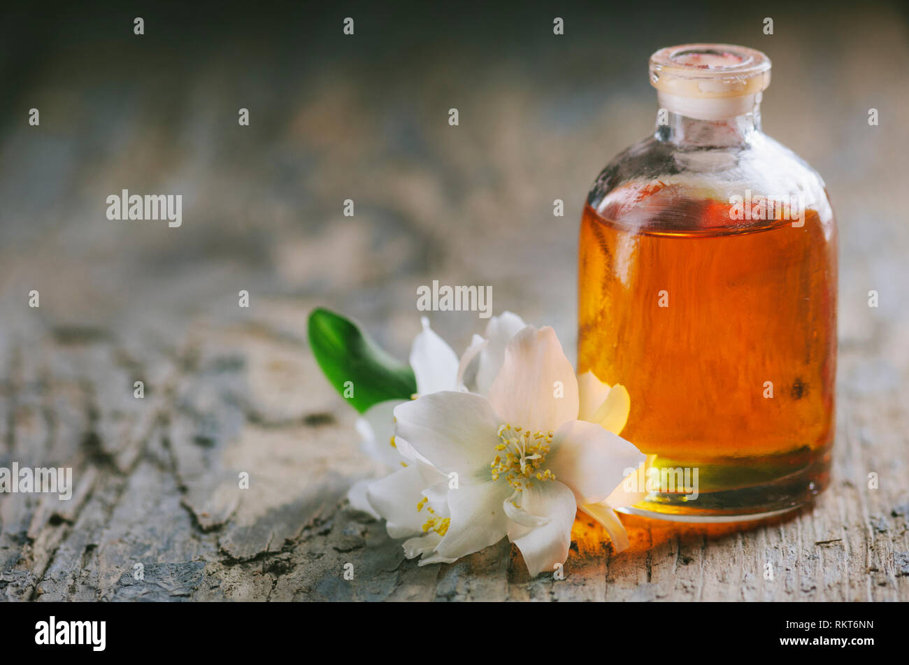 Olio essenziale di fiori di gelsomino. Massaggio Aromaterapico Olio su legno rustico sfondo. Foto Stock