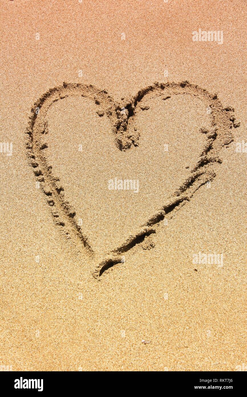 Disegno del dito su di una spiaggia di sabbia - forma di cuore, simbolo dell'amore. Foto Stock