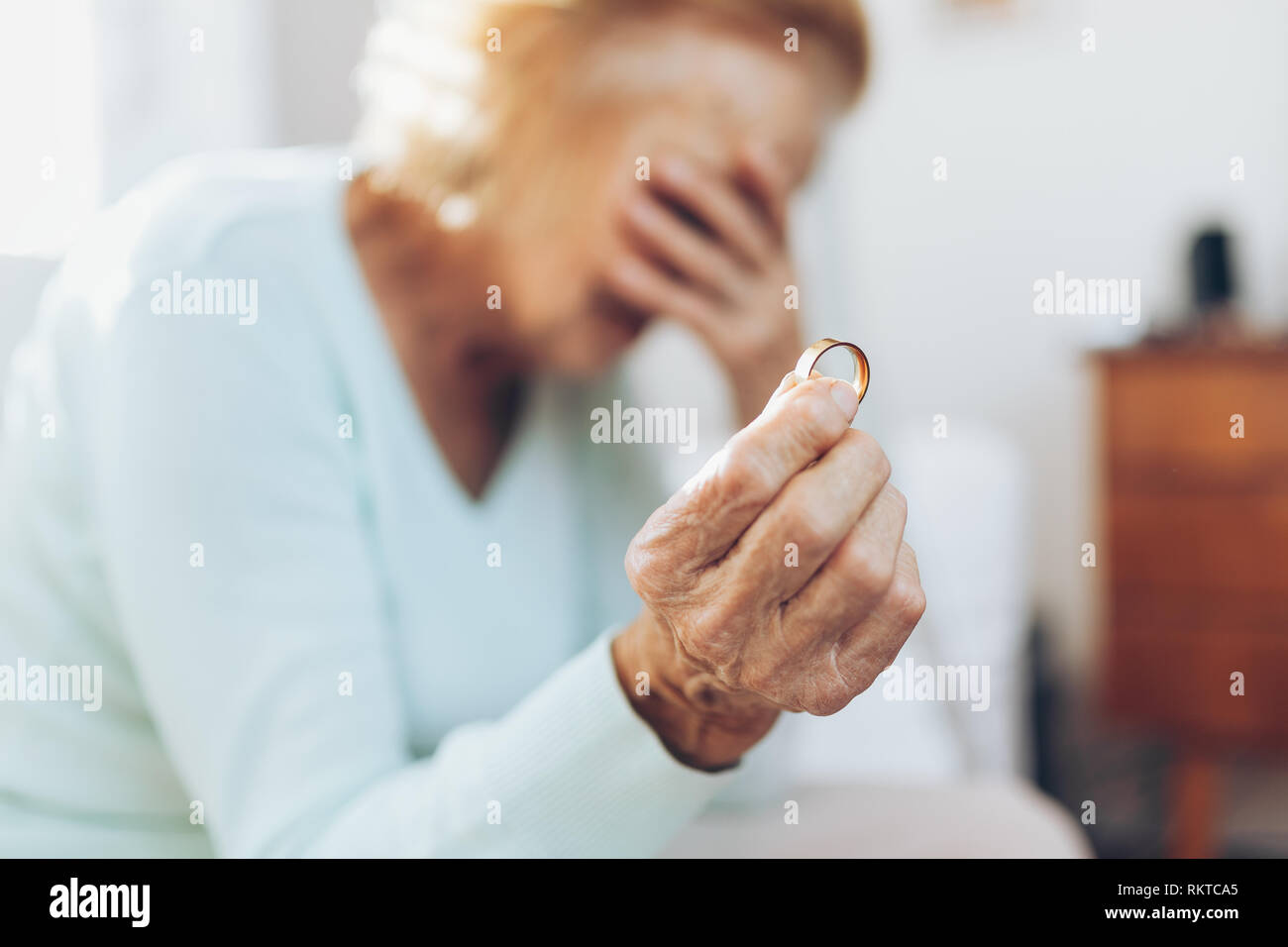 Heartbroken donna anziana tenendo egli mariti anello di nozze Foto Stock