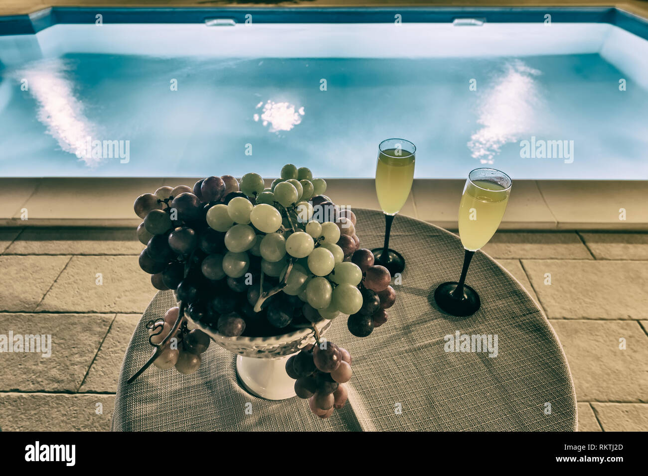 Ciotola con uve e fresco drink vicino alla piscina Foto Stock