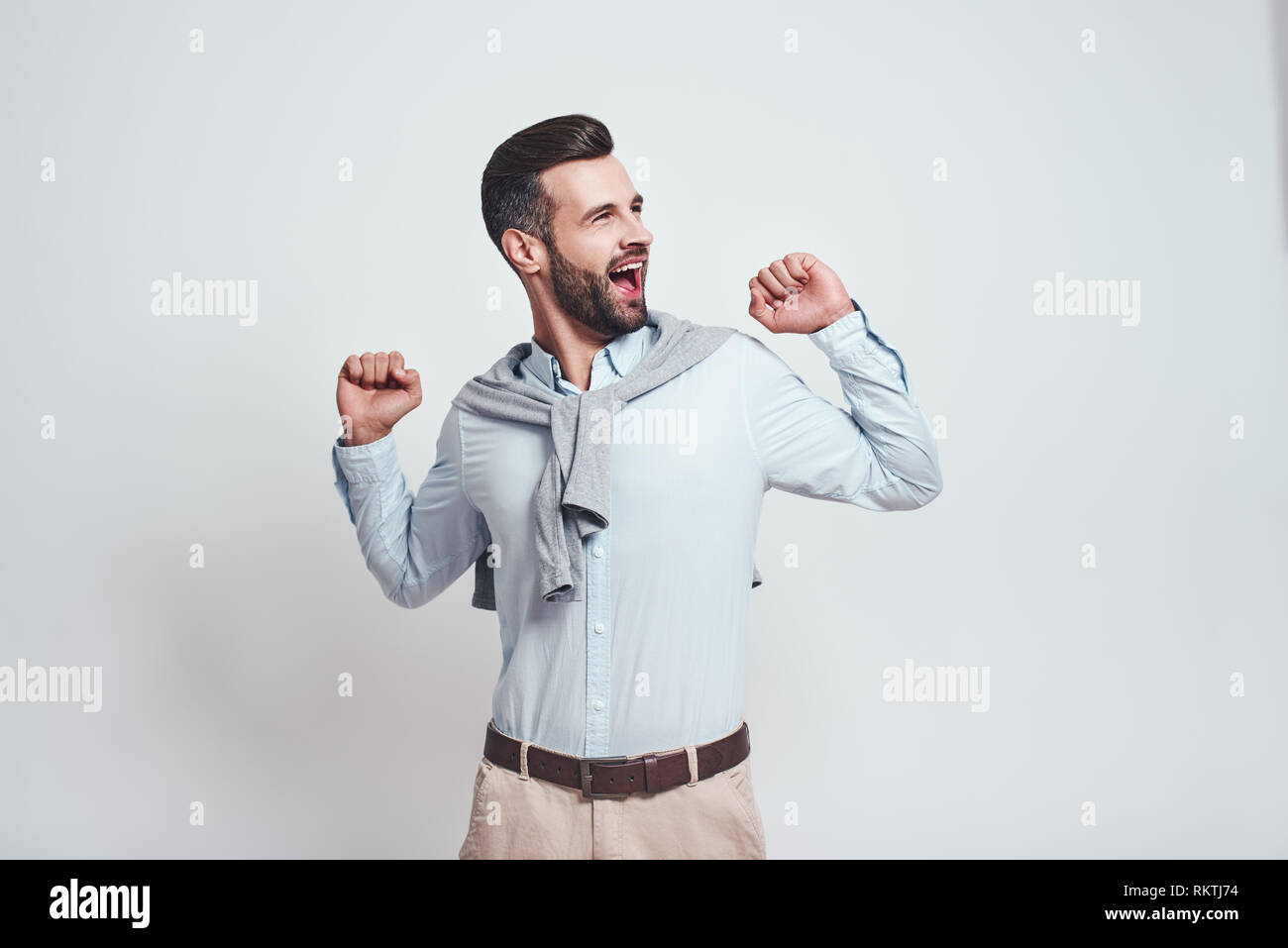 Provare a tenere a. Giovane uomo barbuto è a sbadigliare e sensazione di stanchezza in studio su sfondo grigio. La stanchezza. Close-up Foto Stock