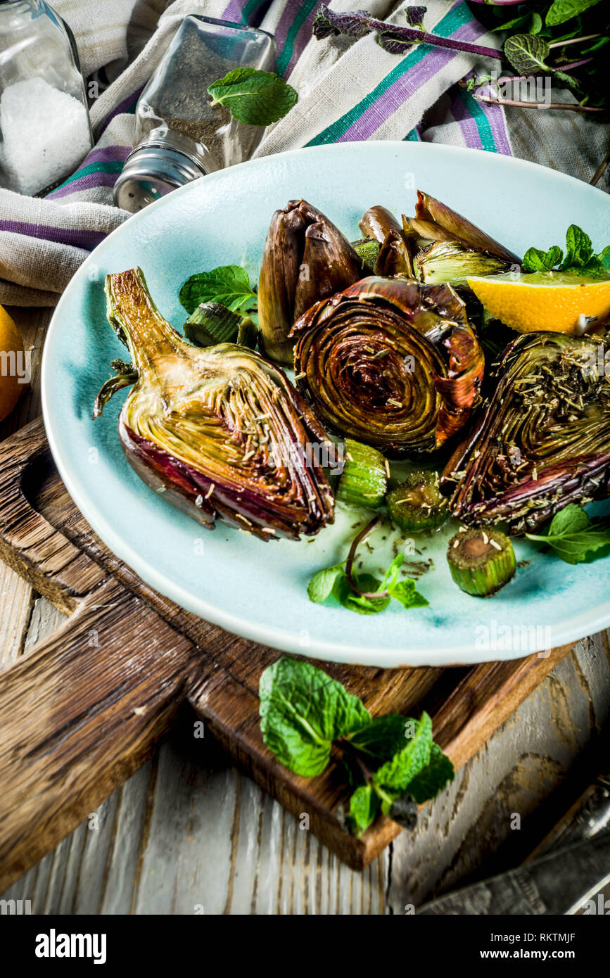 Cuocere al forno, carciofi alla romana e grigliate di fiori di carciofo con olio di oliva, limone, aglio, menta e spezie. Spazio di copia Foto Stock