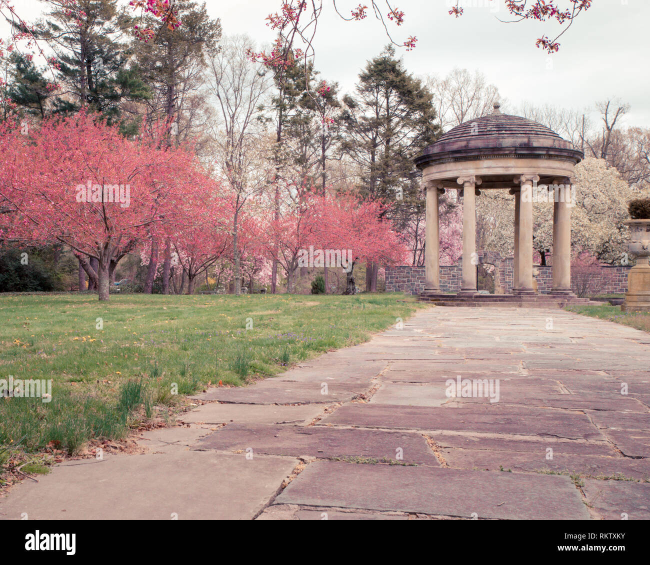 Bellissimo giardino di primavera scena con colorati ciliegi fioriti e classica gazebo in pietra Foto Stock