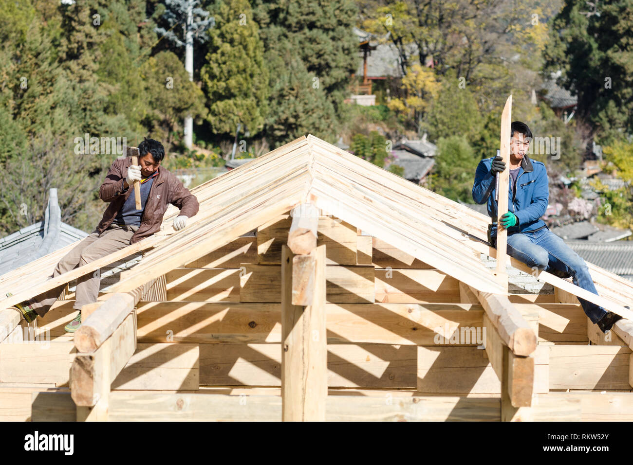 Cinese due lavoratori edili su un tetto di legno struttura, Lijiang, Cina Foto Stock