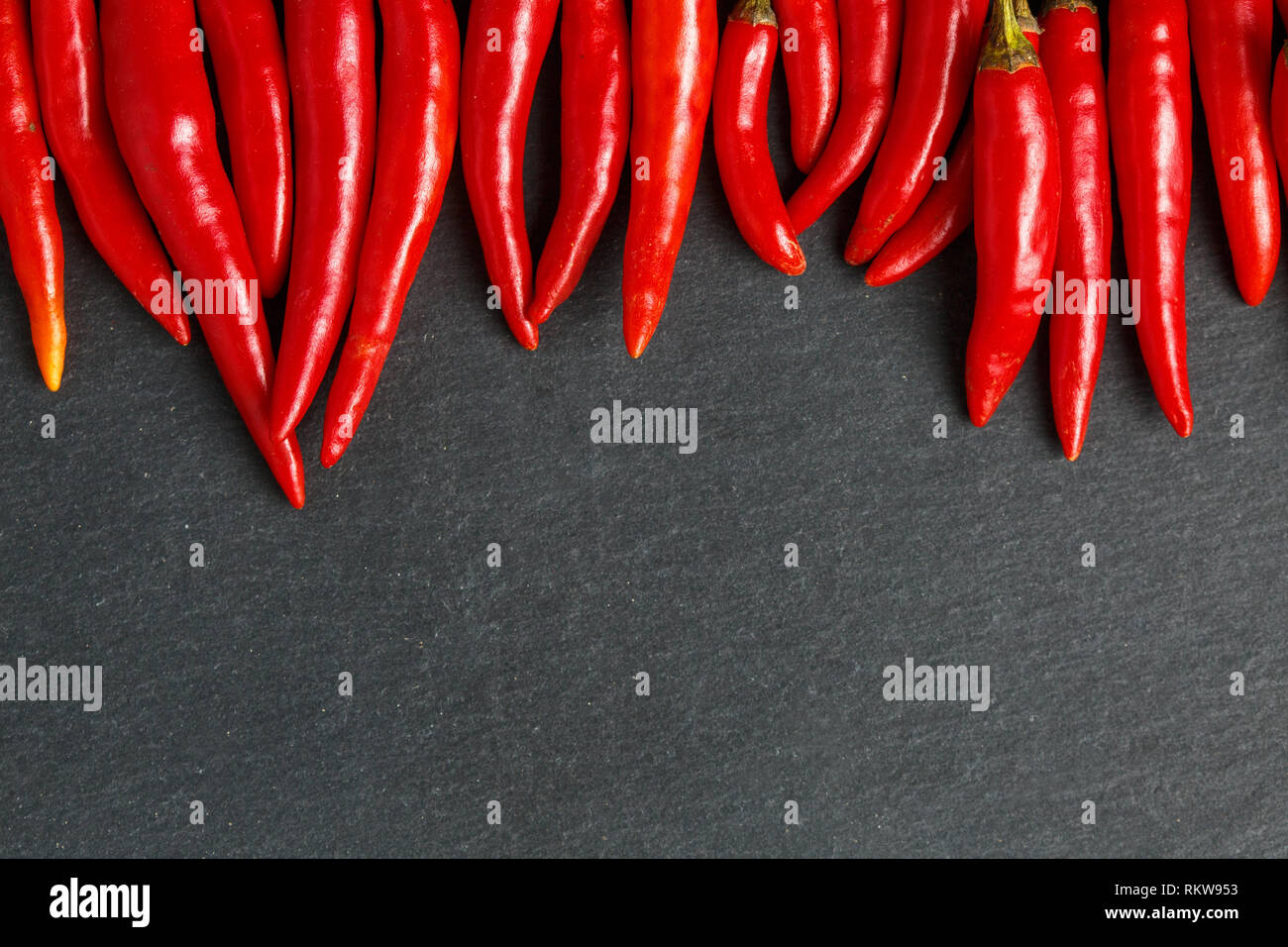 Fresche e mature red hot chili peppers su una pietra nera sullo sfondo Foto Stock