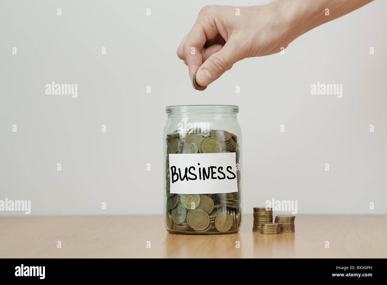 La distribuzione di contante concetto di risparmio. Mette mano monete al vetro casse con iscrizione "business" Foto Stock