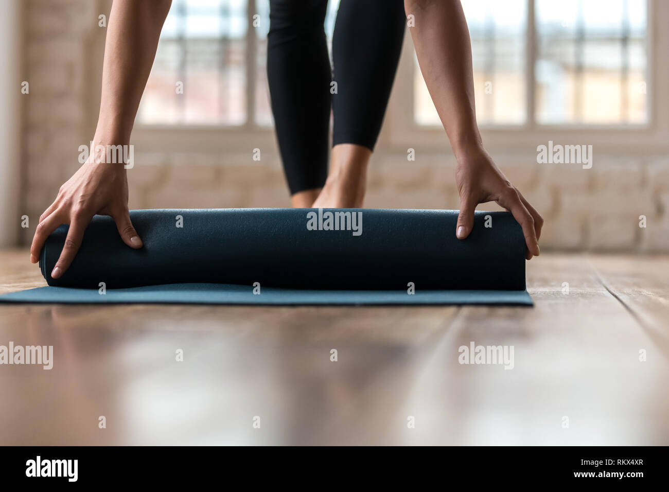 Close up della donna di rotolamento tappetino fitness dopo il corso di formazione Foto Stock