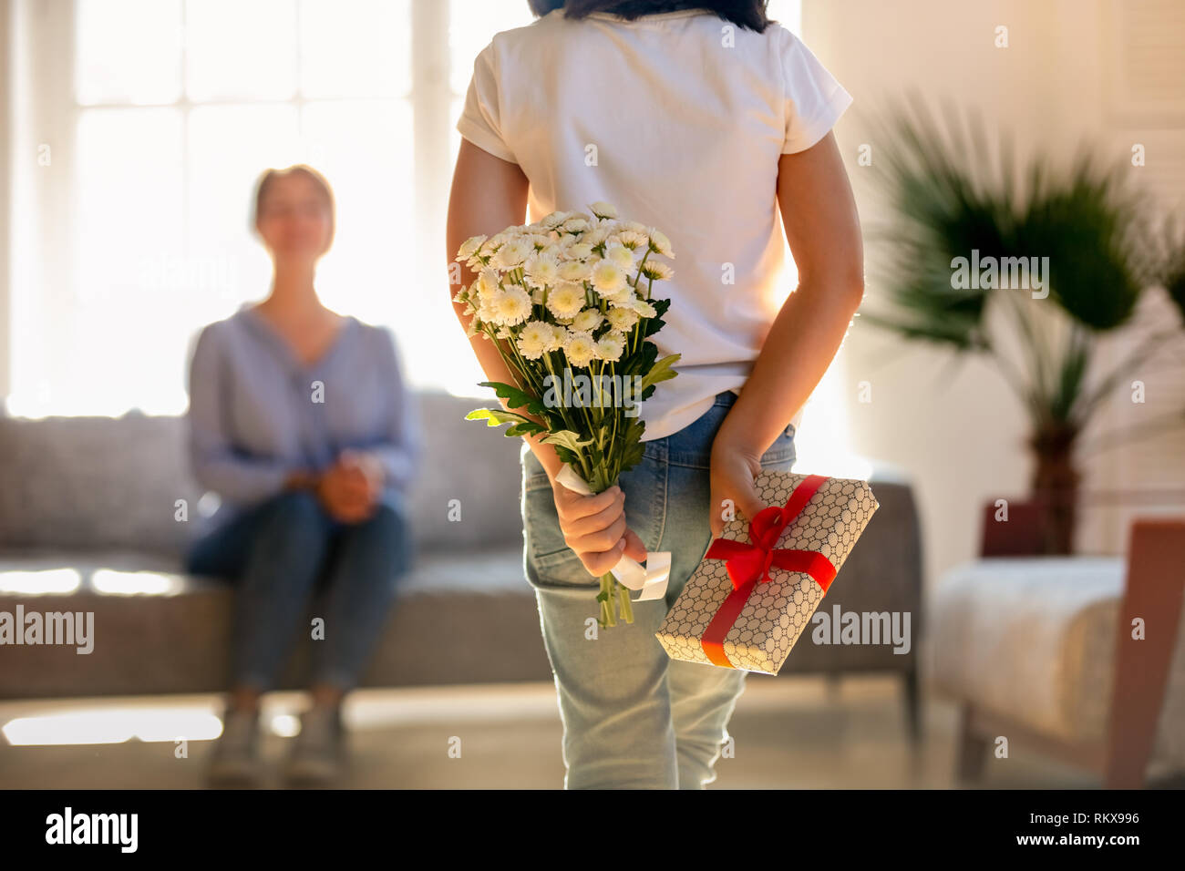 Vista posteriore al kid figlia azienda fiori e confezione regalo Foto Stock