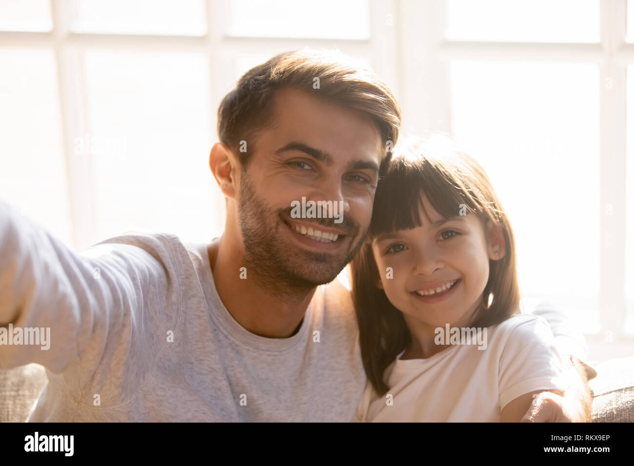 Padre e figlia di capretto con volti felici in posa tenendo selfie Foto Stock