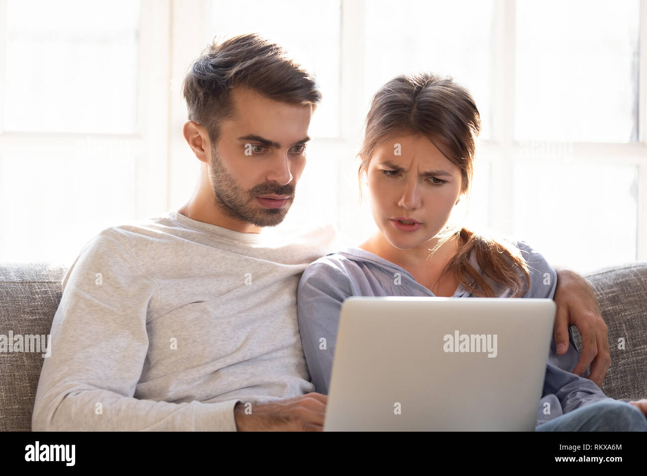 Confuso perplesso moglie e scioccato frustrato marito la lettura di notizie online Foto Stock
