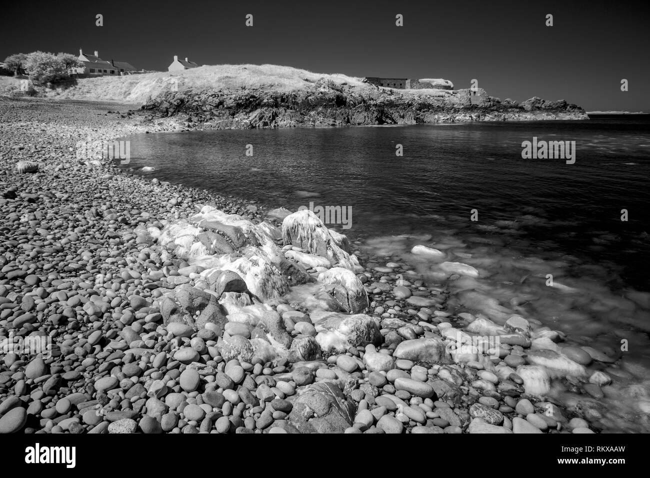 Infrarossi immagine monocromatica di spiaggia scontrosa, scontrosa Bay, vicino al molo su Alderney, Isole del Canale. Foto Stock