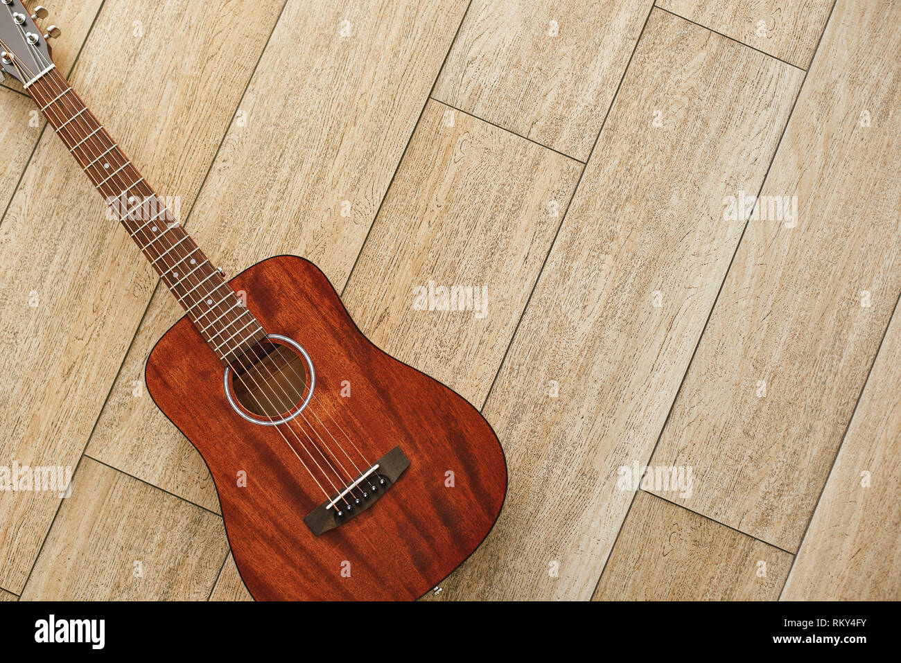 La bellezza di strumento musicale. Vista superiore del brown chitarra acustica sdraiato sul pavimento in legno. Musica di sottofondo. Il concetto di musica. Strumenti musicali Foto Stock