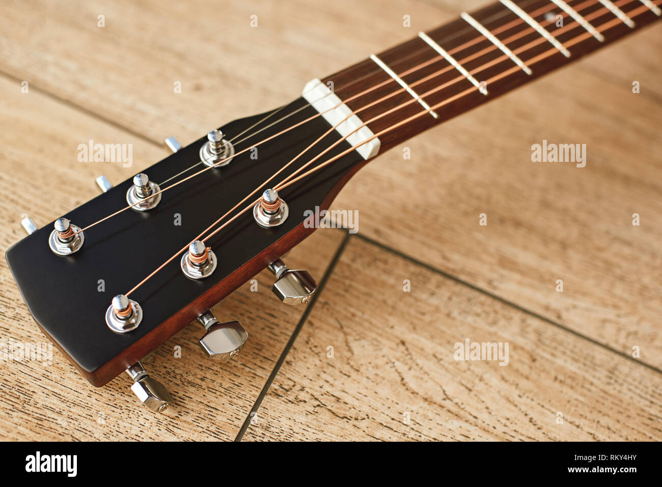 Parte superiore della chitarra. Vista ravvicinata della paletta per chitarra con i tasti tuning per regolare le corde di una chitarra. Sfondo di legno. Il concetto di musica. Strumenti musicali Foto Stock