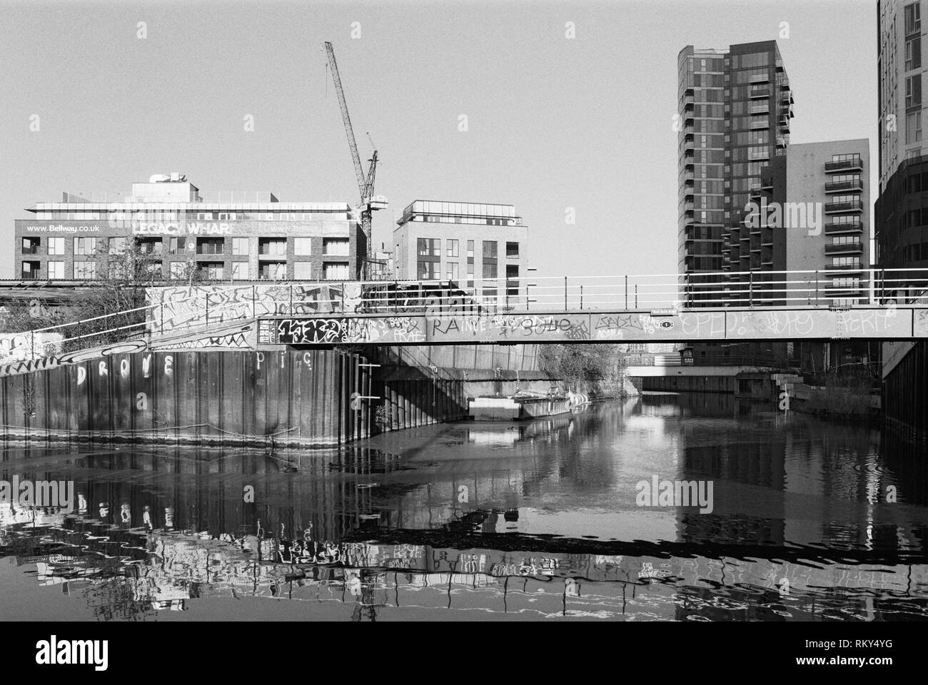 Il Footbridge con graffiti sulla prua torna River, visto dal fiume Lea vicino Bromley-By-Bow, East London UK, con nuovi appartamenti in background Foto Stock