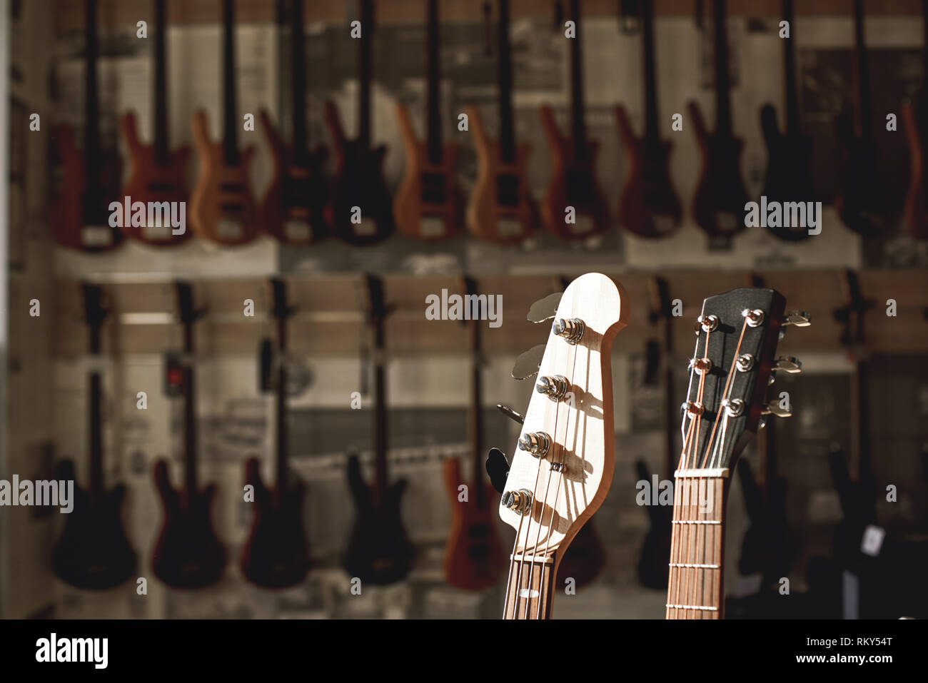 Vista ravvicinata di due paletta chitarra contro di una fila di diverse chitarre elettriche allineate in un negozio di musica showroom. Strumenti musicali. Music store. Il corpo della chitarra Foto Stock