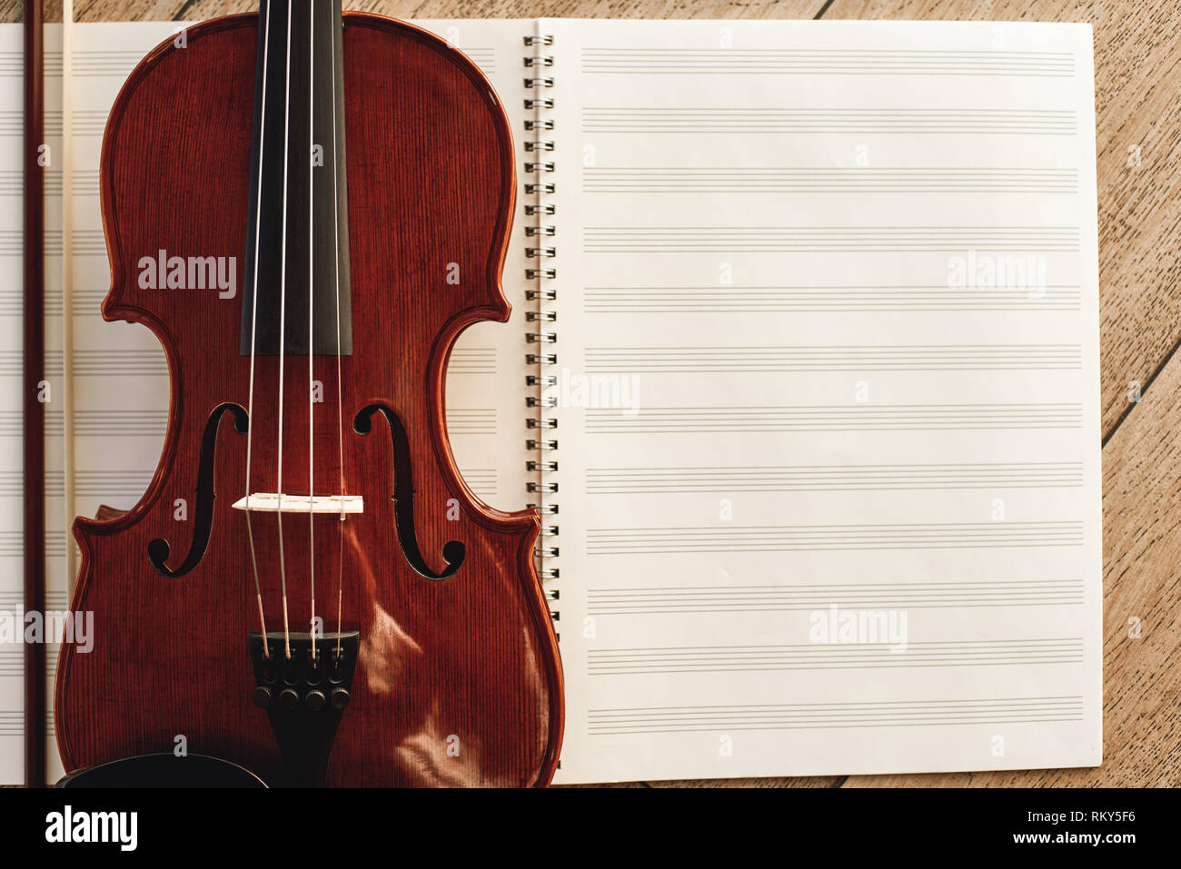 La composizione per il violino. Vista superiore della bella brown violino giacente su fogli di note musicali. Lezioni di violino. Strumenti musicali. Attrezzature musicali. Foto Stock