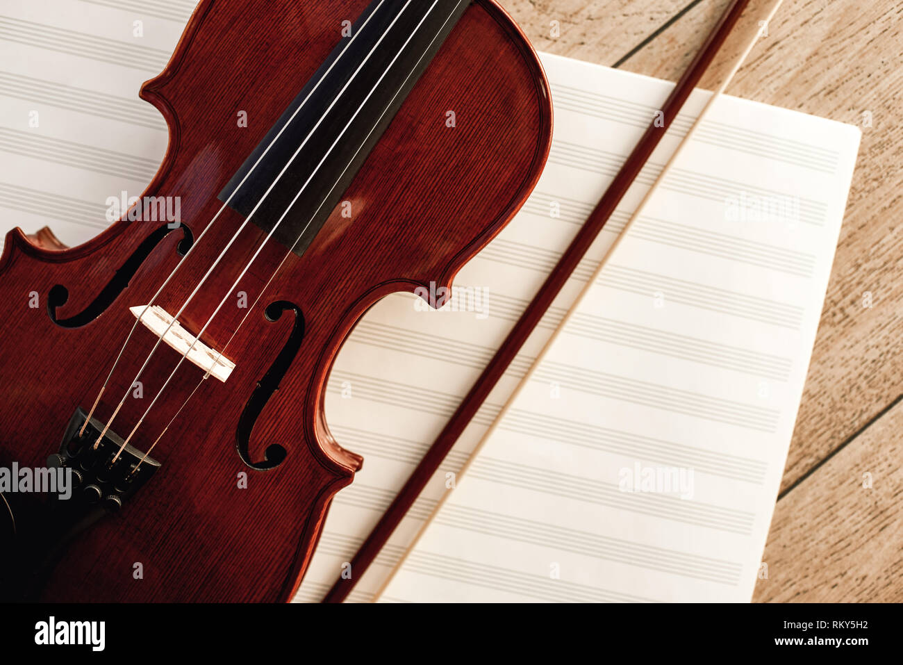 Arte della composizione. Vista ravvicinata del marrone del violino con un inchino giacente su fogli di note musicali. Lezioni di violino. Strumenti musicali. Attrezzature musicali. Foto Stock