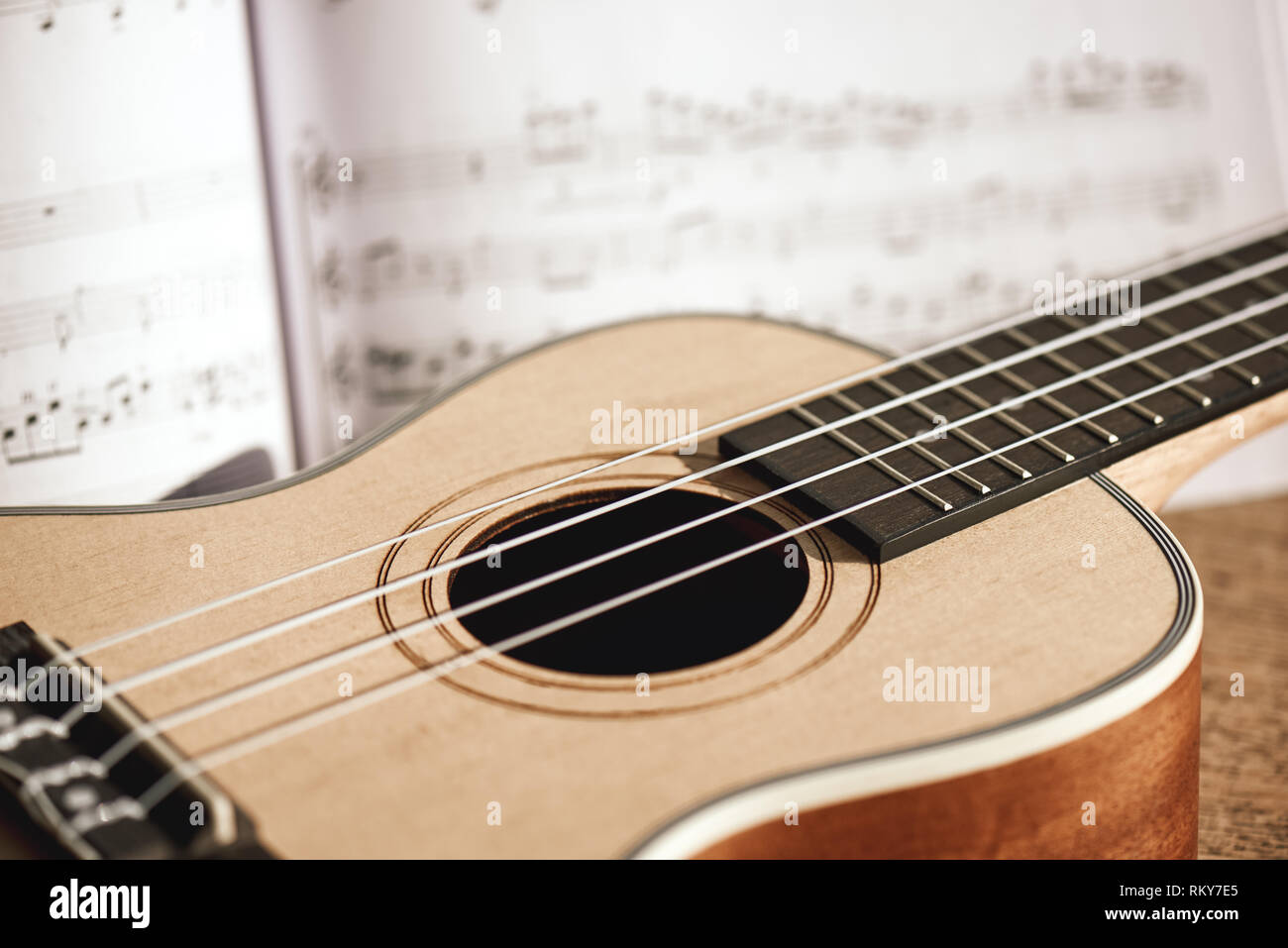 Le corde di Ukulele. Close-up foto di ukulele chitarra e note musicali contro di sfondo di legno. Foto Stock