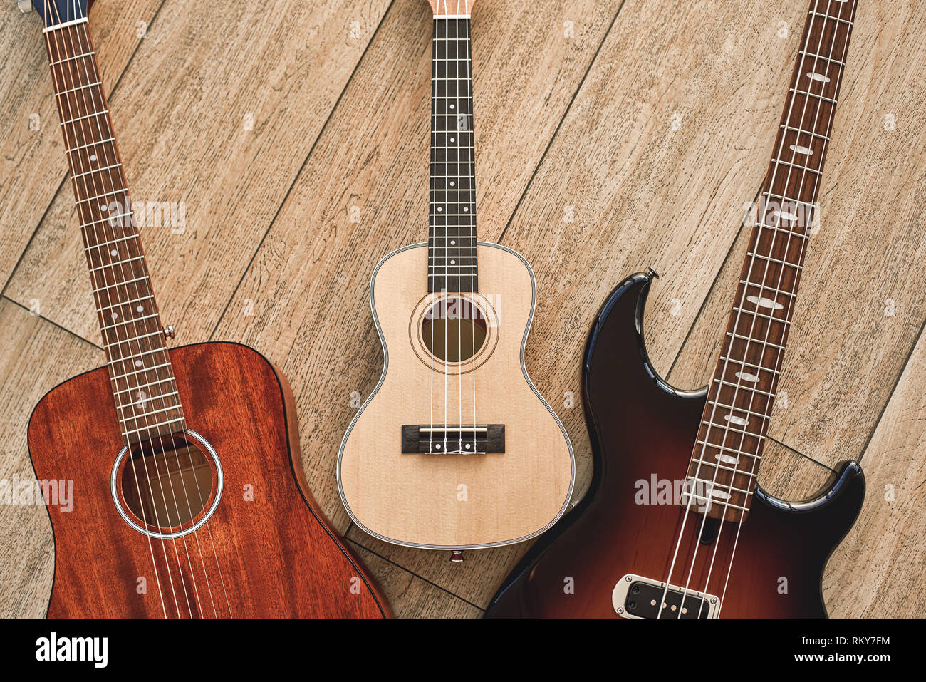 Come scegliere la tua prima chitarra? Vista dall'alto su diversi tipi di chitarre: acustica, elettrica e ukulele. Strumenti musicali. Attrezzature musicali Foto Stock