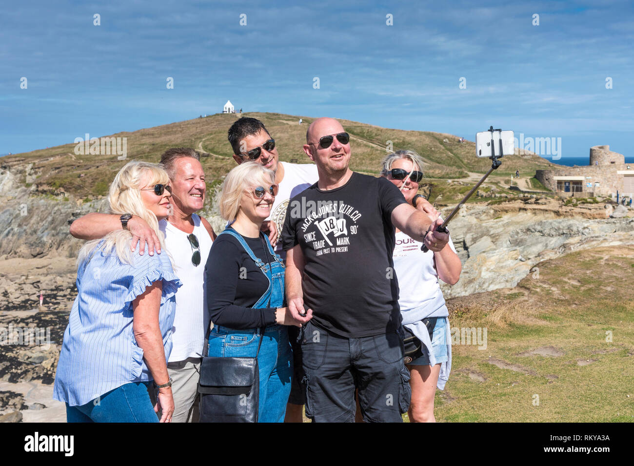 Un gruppo di turisti felici in posa per una fotografia selfie sulla costa a Newquay in Cornovaglia. Foto Stock