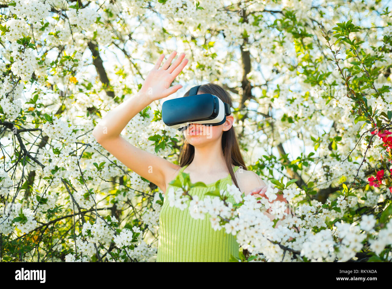 Entrando nel futuro. Ragazza carina giocare in giardino di primavera. Signora giovane indossare occhiali vr in primavera fioriscono. Innovativa tecnologia di VR. La tecnologia virtuale Foto Stock