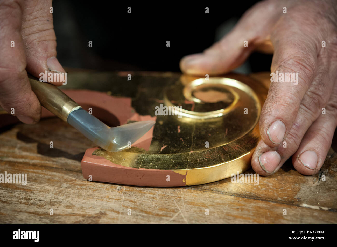 Artigiano utilizza l'agata pietra per il procedimento di brunitura. Tecnica di doratura. Foto Stock