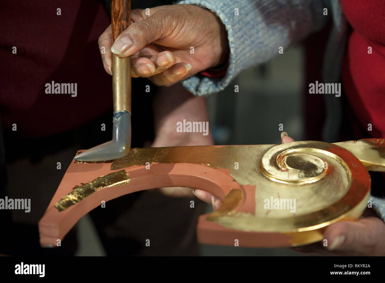 Artigiano utilizza l'agata pietra per il procedimento di brunitura. Tecnica di doratura. Foto Stock