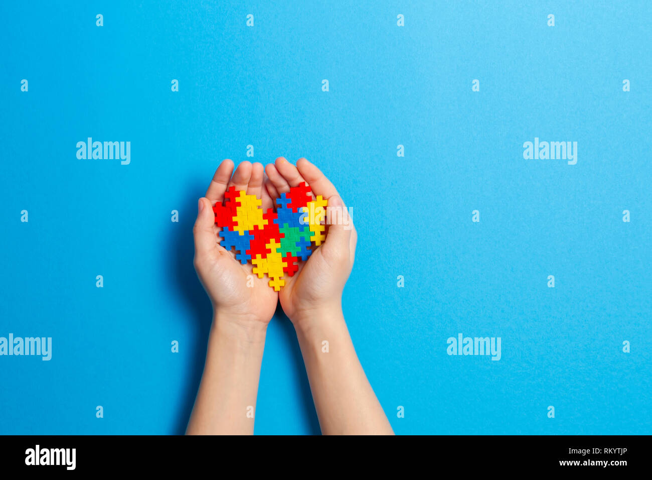 Bambino mano azienda cuore colorati su sfondo blu. Mondo autismo consapevolezza giorno di concetto Foto Stock