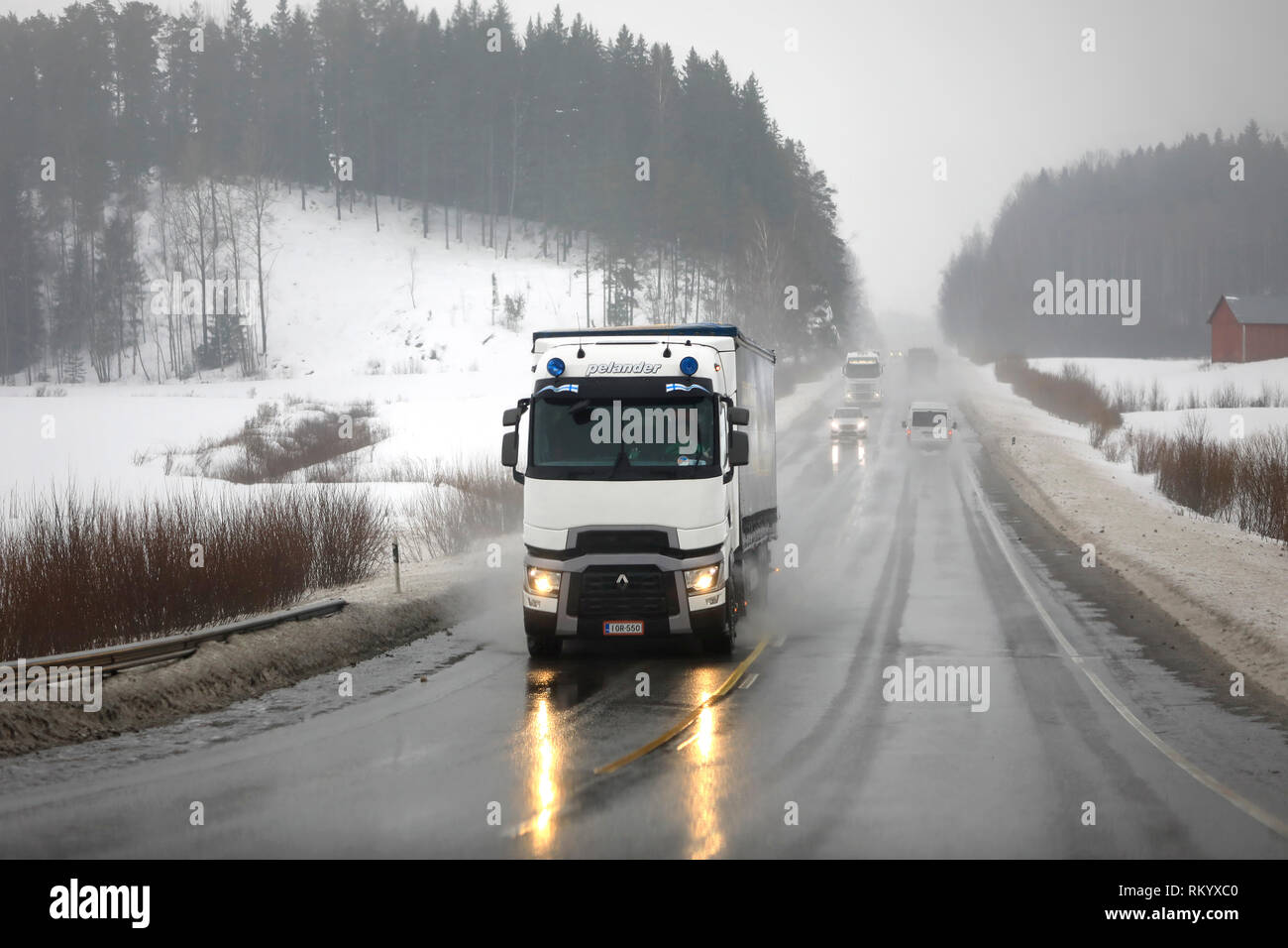 Salo, Finlandia - 8 Febbraio 2019: Bianco Renault Trucks T semi rimorchio di Pelander trasporta merci in un giorno di pioggia di inverno fra il traffico autostradale. Foto Stock