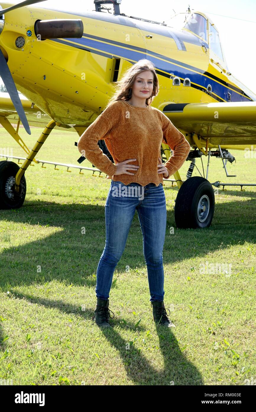 Bel paese ragazza con lunghi capelli fluenti vestito in jeans e un maglione poste con raccolto spolvero aeroplano Foto Stock