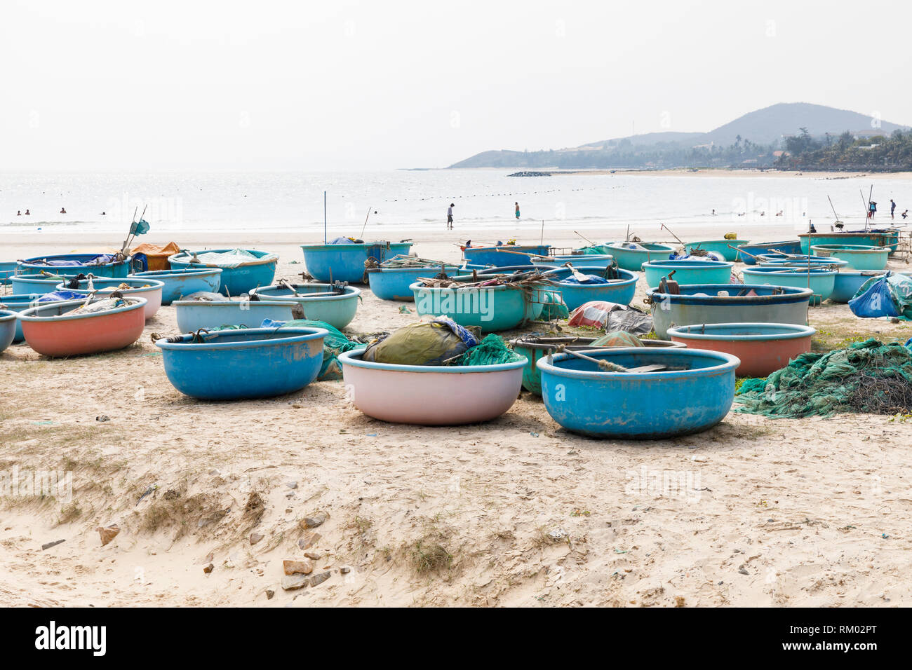 Molti round barche da pesca a secco su terreno sabbioso a fronte di acqua in Phan Thiet, Vietnam Foto Stock