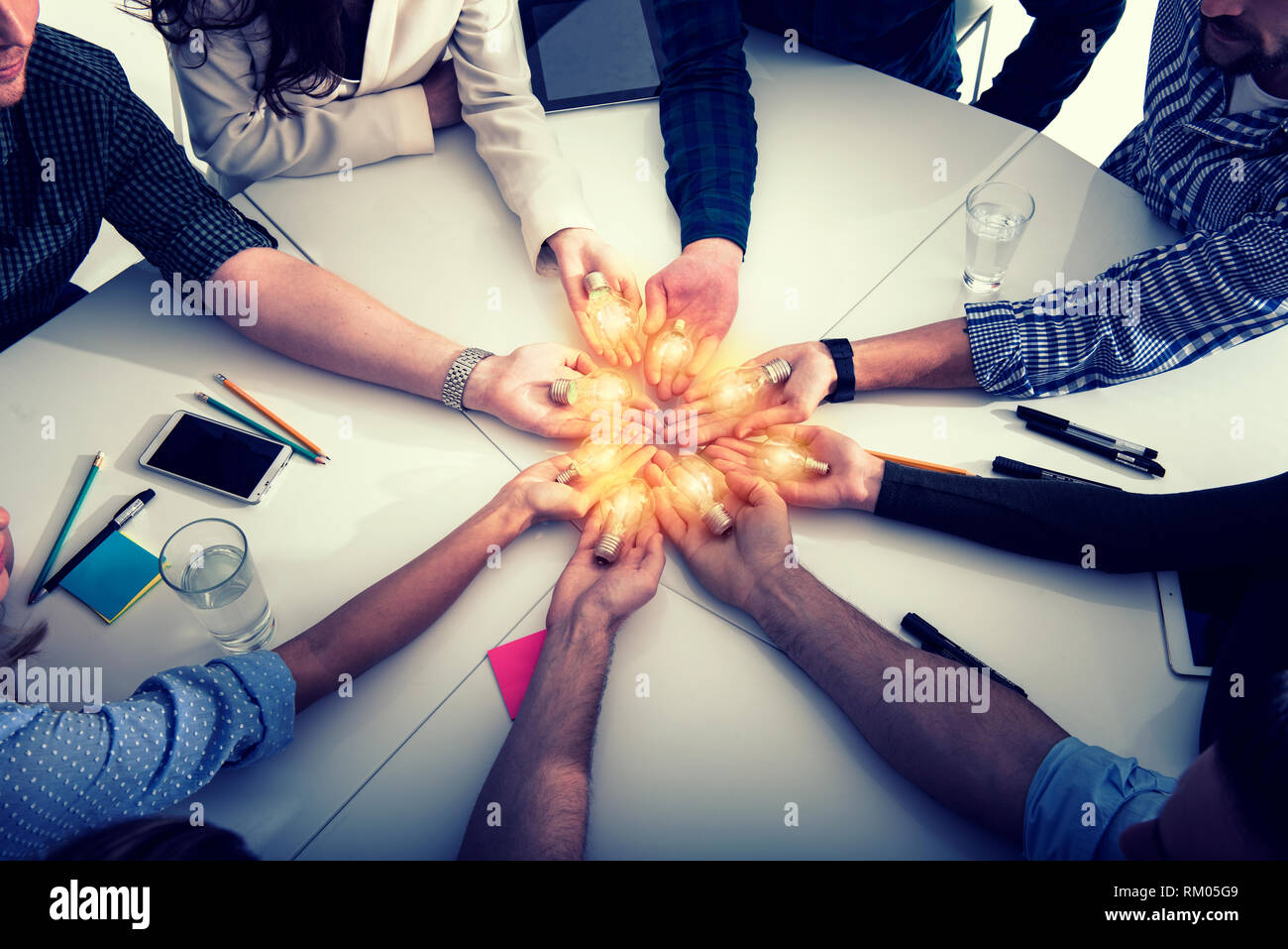 Il lavoro di squadra e il concetto di brainstorming con gli imprenditori che condividono un'idea con una lampada. Concetto di startup Foto Stock